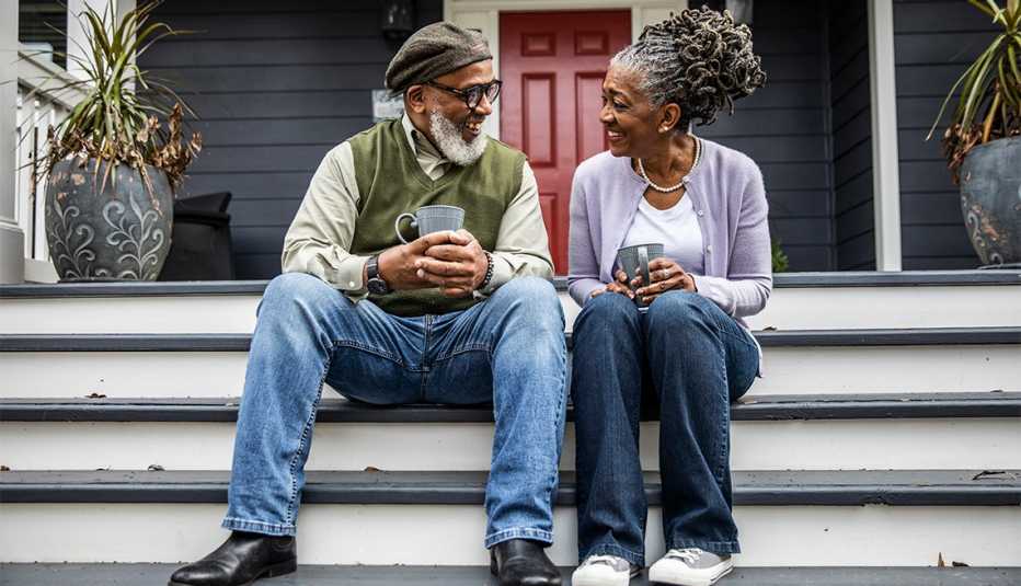 couple having coffee in front of suburban home