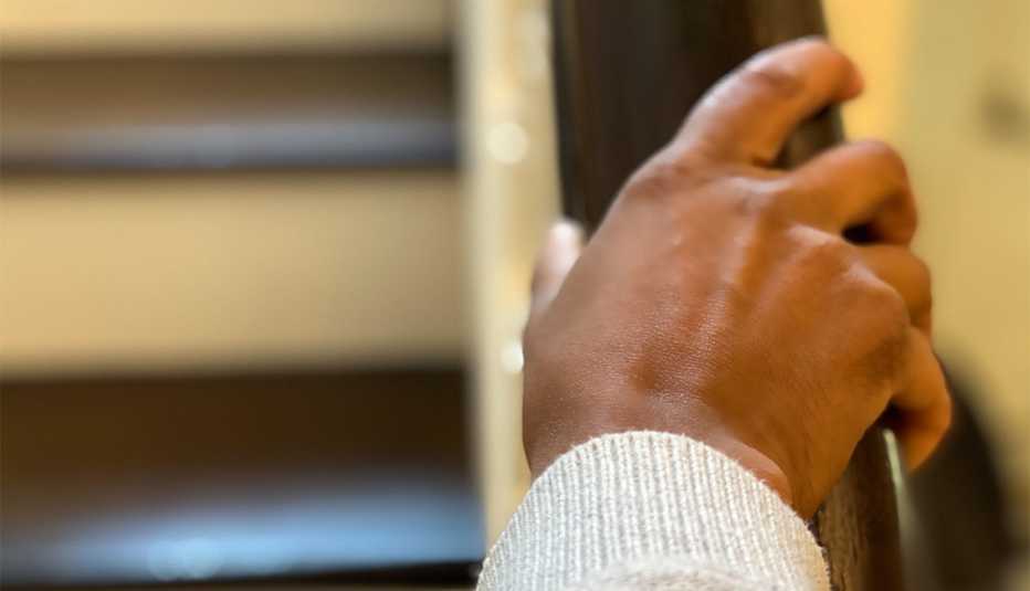 woman holds handrail while climbing stairs