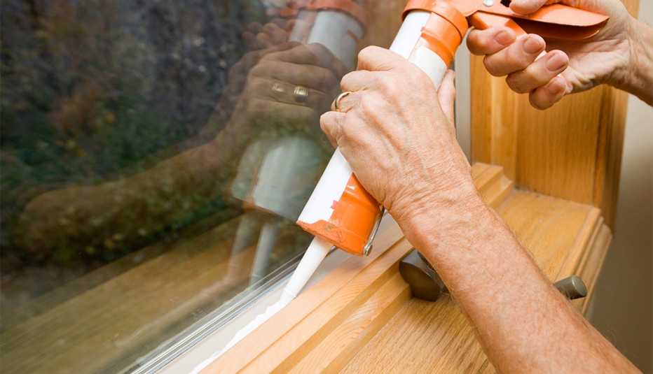 person caulking a window sill
