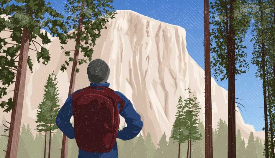 Man in winter clothes with a backpack looks at a mountain through evergreen trees at Yosemite National Park Man in winter clothes with a backpack looks at a mountain through evergreen trees at Yosemite National Park