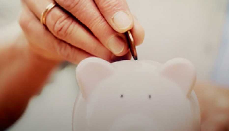 Person depositing a coin in a piggy bank