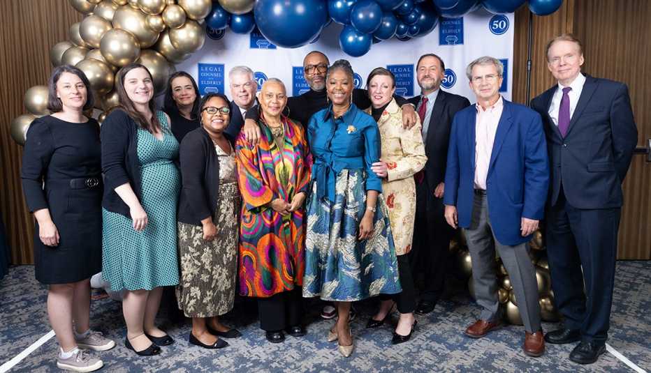 a group of twelve people posing in front a baloon arch