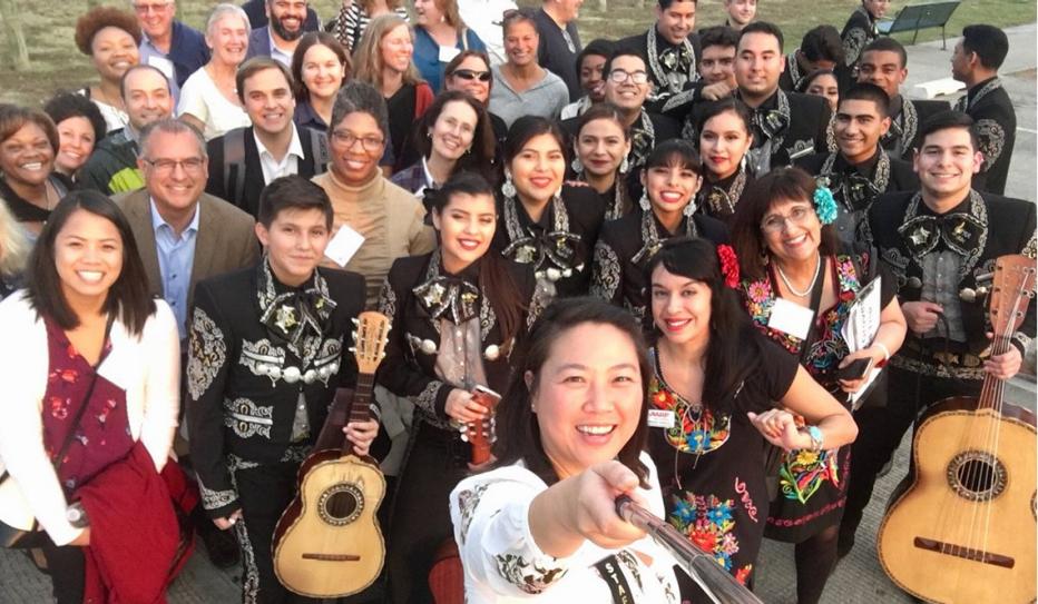 Attendees at the 2017 AARP Livable Communities pose with a mariachi band in the Trinity Groves area of Dallas, Texas