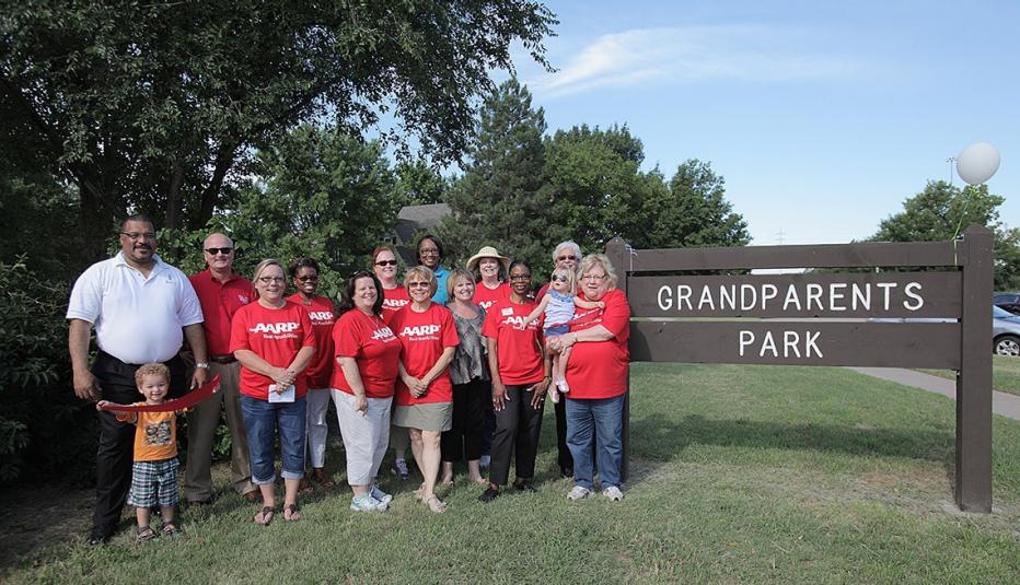 Families pose in front of the sign for the grandparent's park.