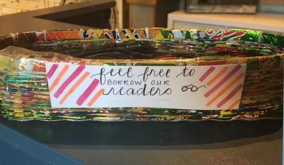 A basket with with a sign that says "Feel Free to Borrow Our Readers"