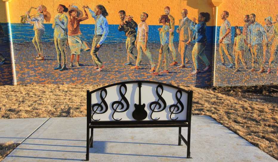 A musically-themed bench, acquired with funds from the AARP Community Challenge, was installed in front of a colorful mural in Hot Springs, Arkansas