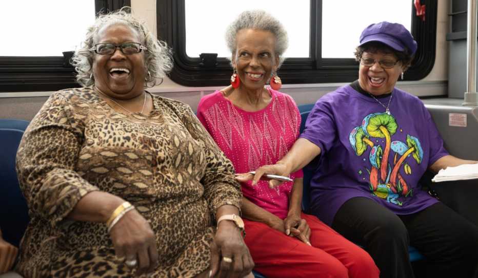 Three women laughing while riding a bus in Kenner, Louisiana