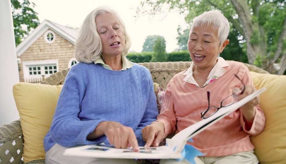 Two Mature Ladies Sitting On Porch And Looking At Photo Album, Livable Communities Two mature women looking at photo album on porch.