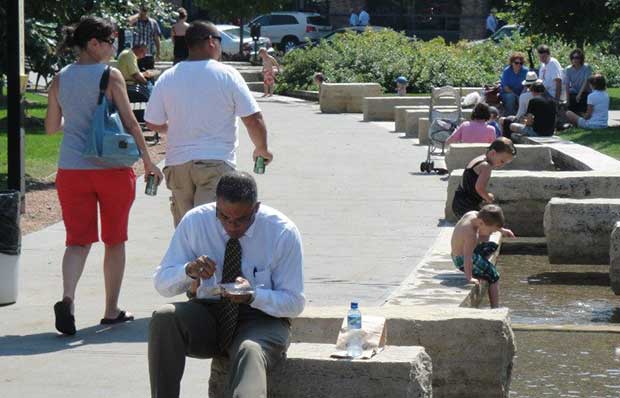 People of all ages relax near a water fountain in Des Moines, Iowa