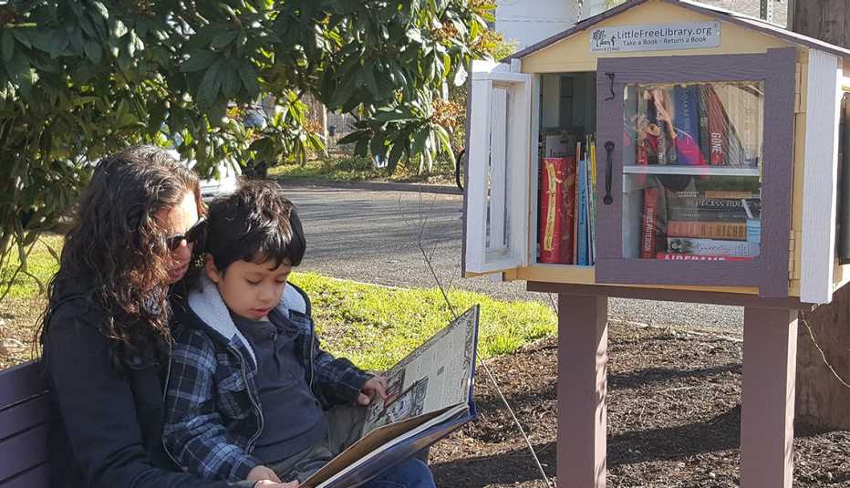 A mother and son read a book next to a Little Free Library in Austin, Texas