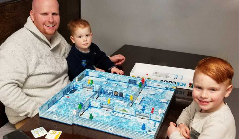 A dad and his two preschool age sons play the board game Ice Cool