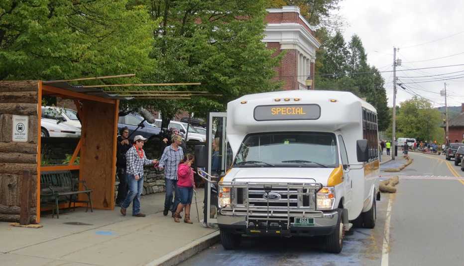 A temporary bus shelter made of logs and wood provides shelter for people as they wait for the shuttle bus.