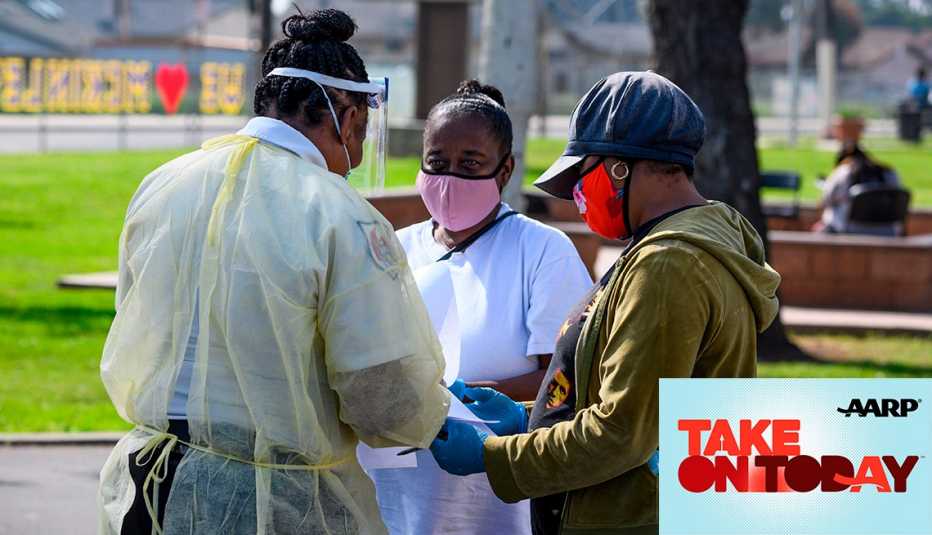 Three women with masks talk in a park