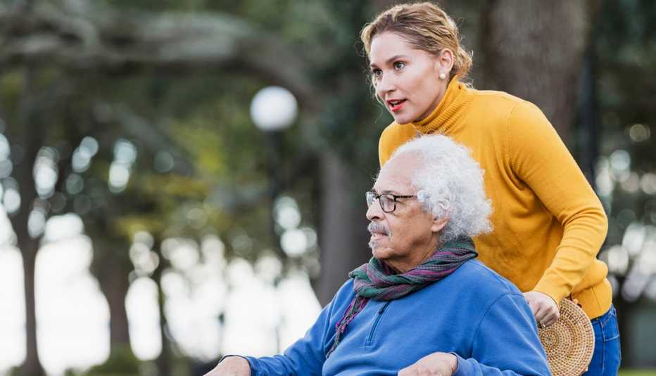 a woman pushing a man in a wheelchair in. a park
