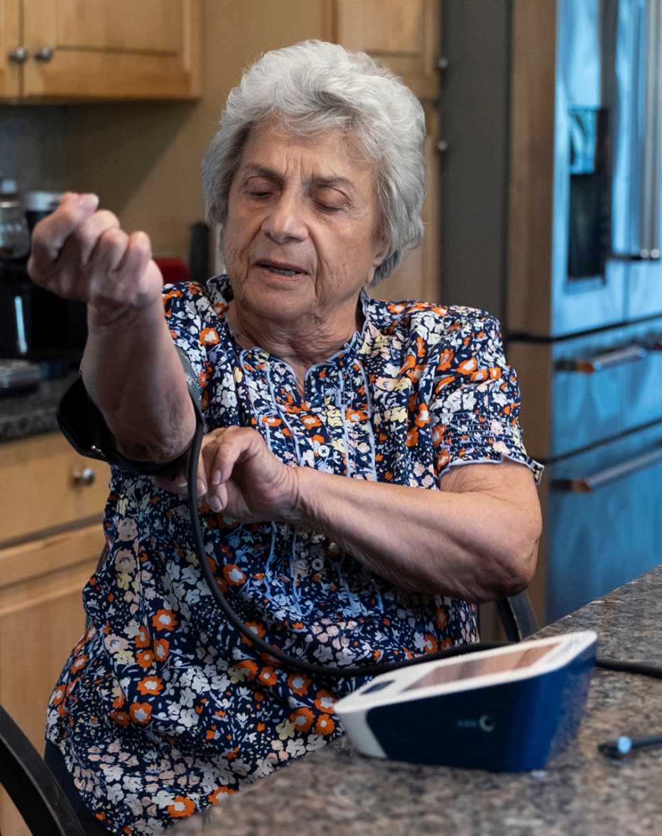 Pat Cutillo, 85, demonstrates the process of checking her blood pressure, which she does twice a day, at her home in Downingtown, Pennsylvania on May 29, 2023. pat cutillo checks her blood pressure