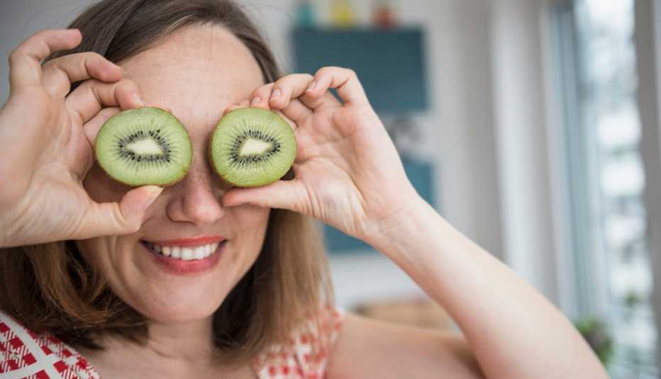 woman holding kiwis up to her eyes