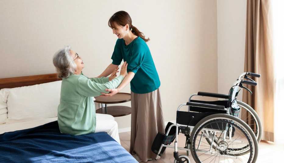 a caregiver helping a woman out of bed and into a wheelchair