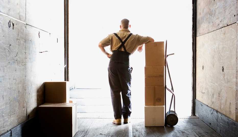 Male warehouse worker in freight truck with boxes, facing outward