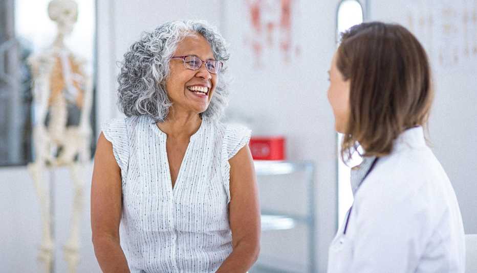 a smiling woman talking to a doctor in a hospital room