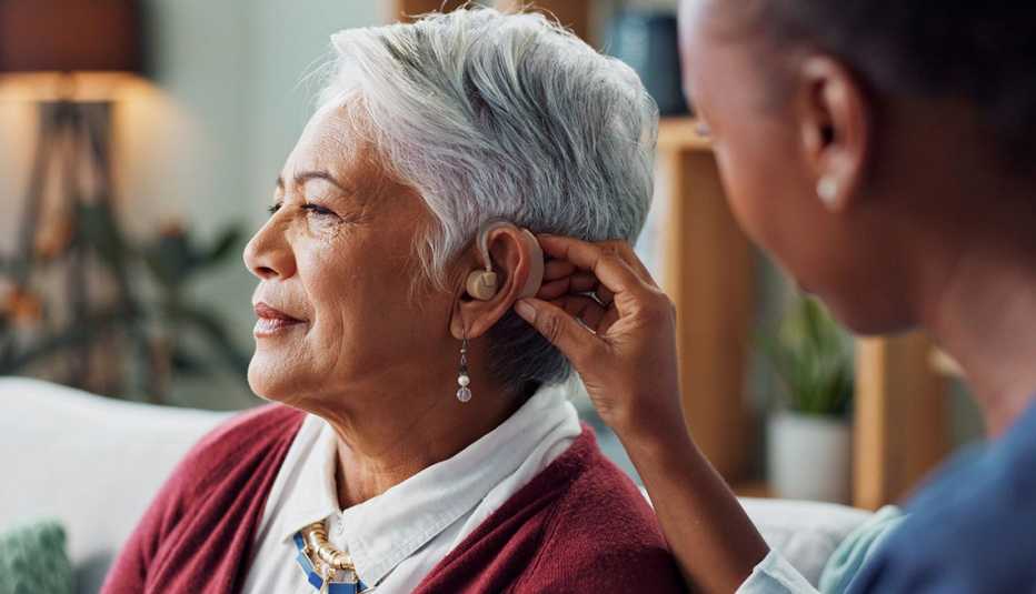 a nurse placing a hearing aid on a woman's ear