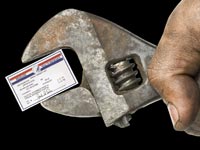 greasy hand holding an adjustable wrench with a Medicare card in its grip.