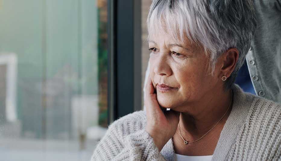 an older woman looking out the window, she appears to be sad