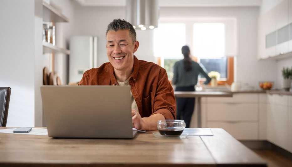 AARP member on laptop in kitchen smiling