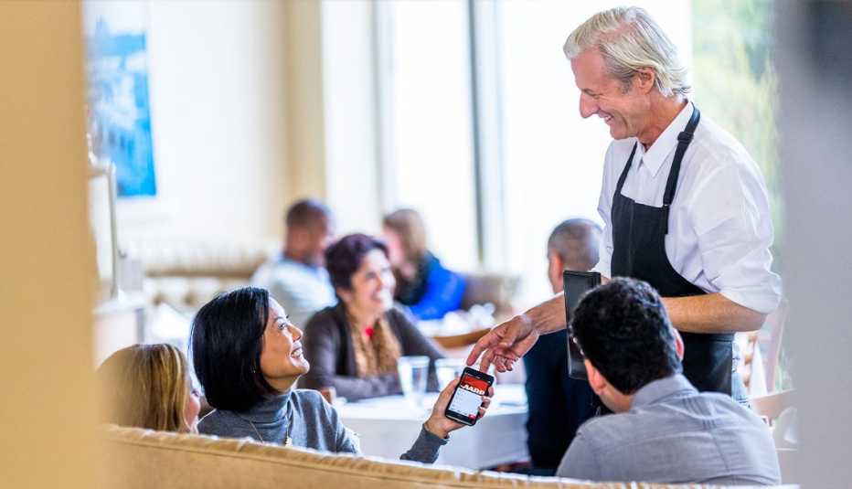 AARP member at restaurant using aarp online membership on phone