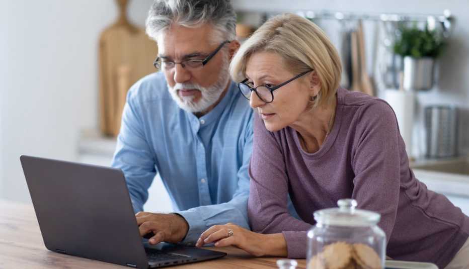 AARP member couple looking at membership add-on options on their laptop in the kitchen
