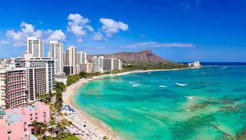 hotel on the beach with volcano mountain in background, turquoise color water and bright blue sky with minimal white puffy clouds