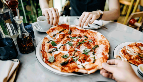 woman and man hands grabbing slices of pepperoni cheese basil pizza on marble restaurant table