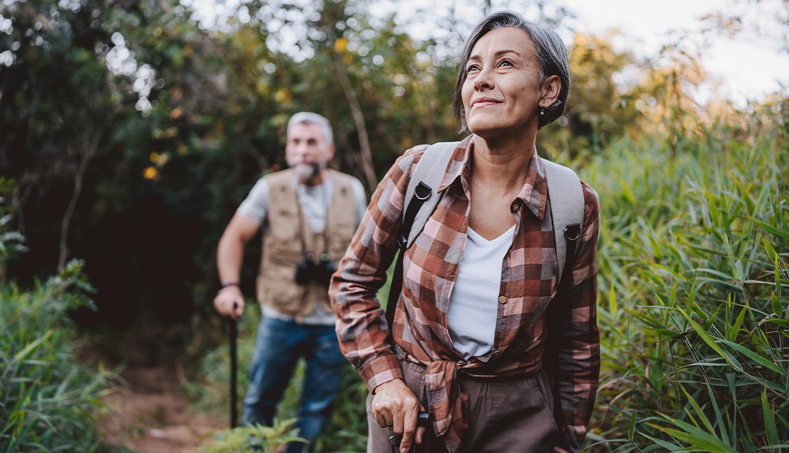 Mature woman and man hiking through the woods on a weekend getaway