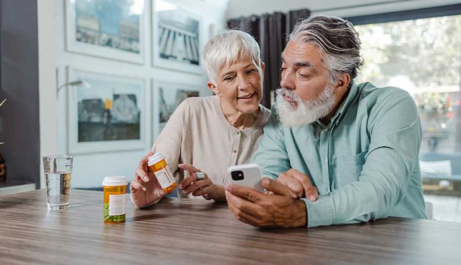 AARP member couple looking at prescription bottles and while sitting together at the kitchen table