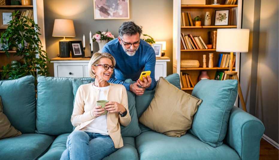AARP Member Couple Looking at Mobile Phone Together on Blue Couch
