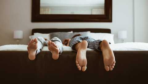 Feet of two people sleeping on bed. People sleeping on bed in different positions.