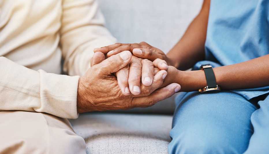 Closeup of elderly man's hands being held by in-home care nurse