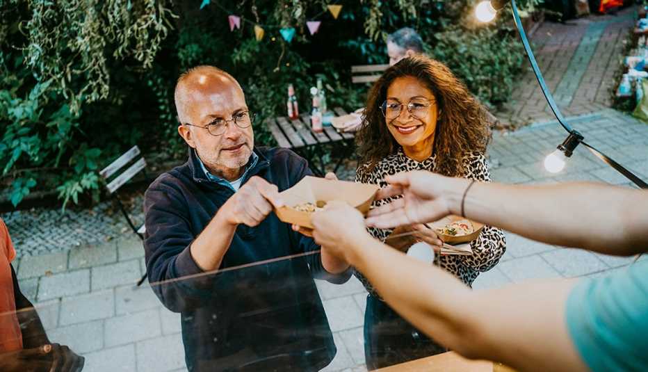 A man and woman grabbing food from a food stand while smiling