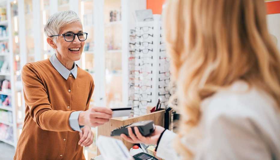 A woman paying for her prescribed medicine and smiling.