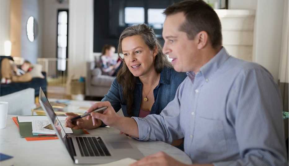 Man and woman working at a table looking at a laptop computer