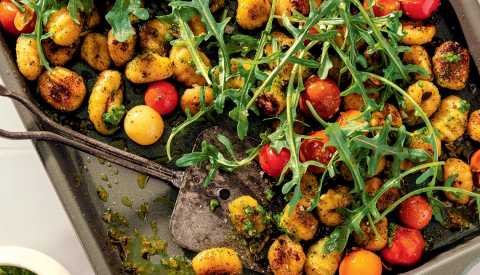 Gnocchi with tomatoes and arugula on pan