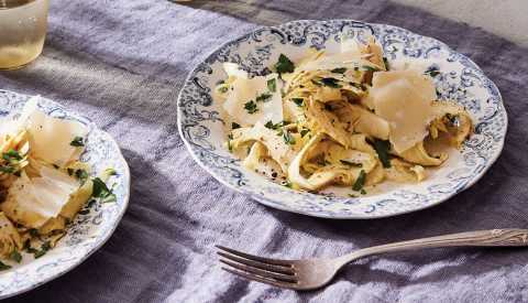 artichoke carpaccio from portico cookbook garnished with parsley on fancy plates with blue designs and a fork