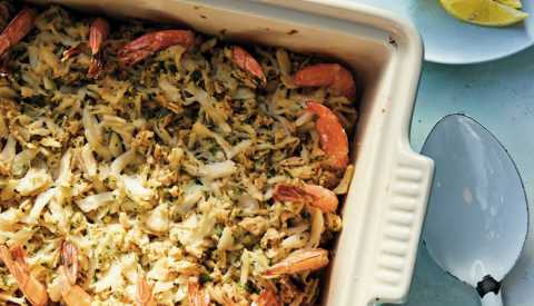 stuffed shrimp casserole with crab meat, cracker crumbs and spices in pan with spoon next to it