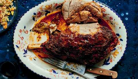 Sikandari Raan — Spiced Leg of Lamb on a decorative plate with a fork and knife. 