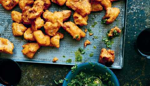 Buttermilk Chicken Pakoras on a blue tray with a bowl of herbs