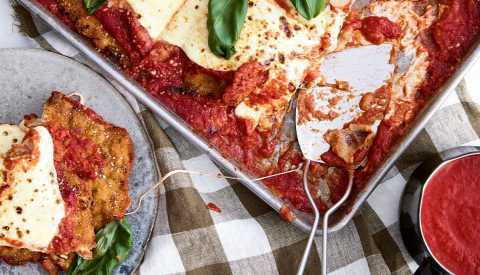 Chicken parm in pan, with piece on plate next to it