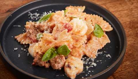 Farfalle, sausage, cheese and basil in marinara sauce on plate