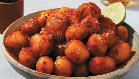 Papitas enchiladas in a bowl with a lime wedge