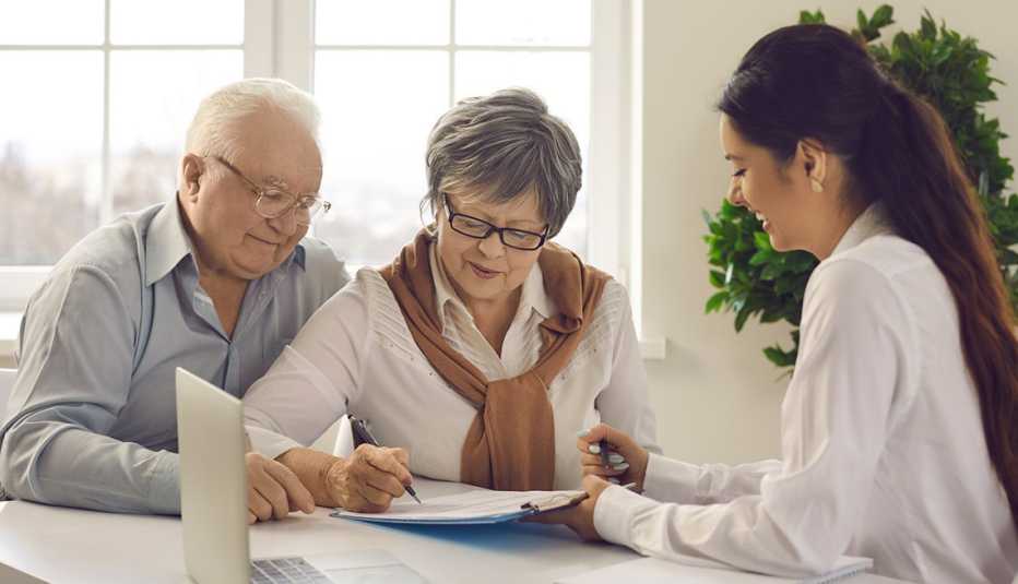 an older couple fills out paperwork with a financial advisor