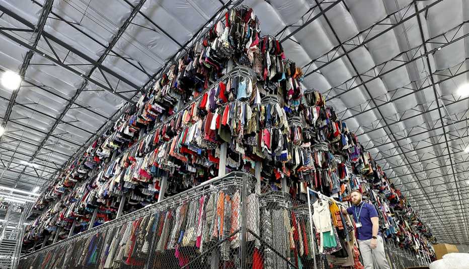 massive warehouse with thousands of garments hung on three-tiered conveyor system at a ThredUp used clothes sorting facility massive warehouse with thousands of garments hung on three-tiered conveyor system at a ThredUp used clothes sorting facility