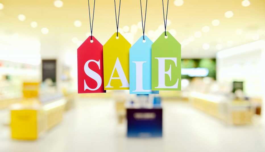 Paper price tags that spell out the word SALE hang from strings in front of a soft focus shop interior. 